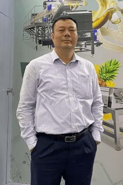 Paul Nguyen (Nguyễn Quyết Thắng), tư vấn công nghệ nhà máy chế biến thực phẩm, đứng trước pano dây chuyền chế biến trái cây